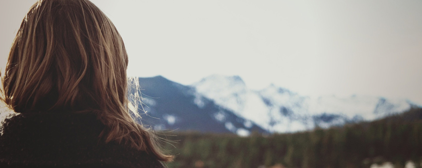 Mulher loira, com cabelos na altura do ombro, olhando para montanhas de gelo à sua frente_Luz da Serra. 